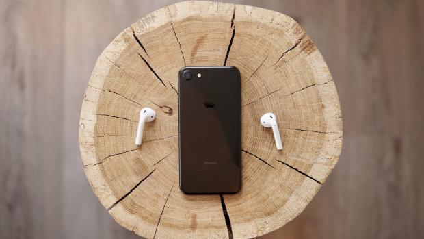 iphone 7 and earpods on a wooden stump